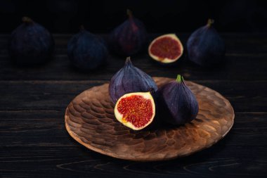 Siyah bir ahşap zemin üzerine bir plaka üzerinde bir kaç incir. Meyve şifa