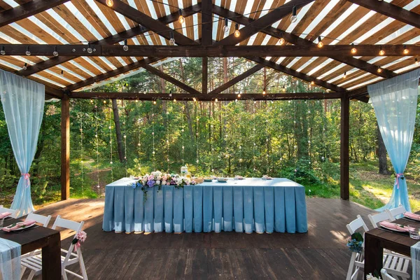 Wedding decor. Table for the newlyweds outdoor. Wedding reception. Elegant wedding table arrangement, floral decoration, restaurant. Wedding in the forest