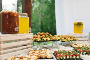 Nikah şekeri nin üzerine cam limonata kavanozları. Catering. Düğünde içki. Ormanda yaz düğünü. Zarif düğün masası aranjmanı