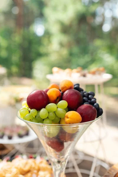Fruits in glass. Wedding decor. Summer wedding in the wood. grapes, apricots, peaches