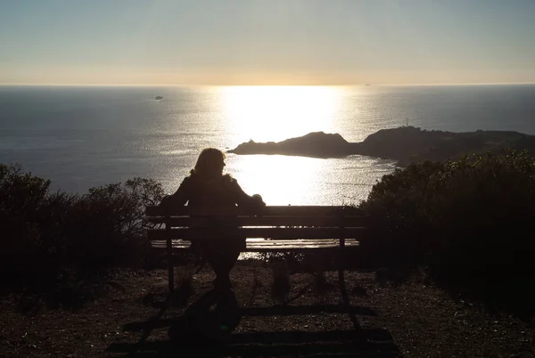 The silhouette of a lonely girl sitting on a bench watching the sunset at san Francisco, California