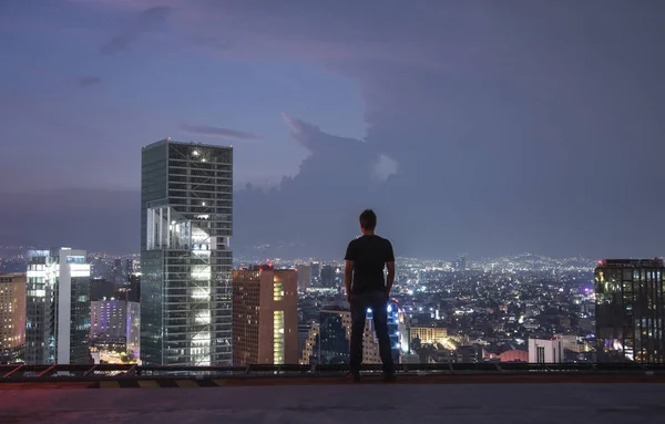 Men standing on the rooftop Mexico city with night downtown view. Mexico City skyline at night from top