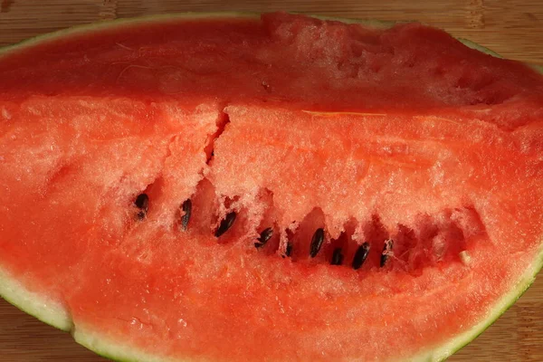 Quarter of ripe juicy watermelon with seeds on a wooden table top. Watermelon pulp with seeds close-up.