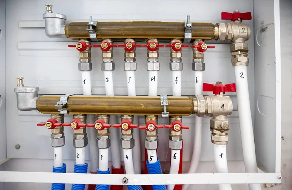 Central heating system pipes. White tubes connection of heating and hot water of the house. Red valves.