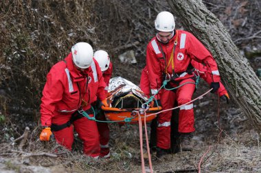 Sofia, Bulgaria - 5 December 2017: Paramedics from mountain rescue service provide first aid during a training for saving a person in accident in the forest. clipart