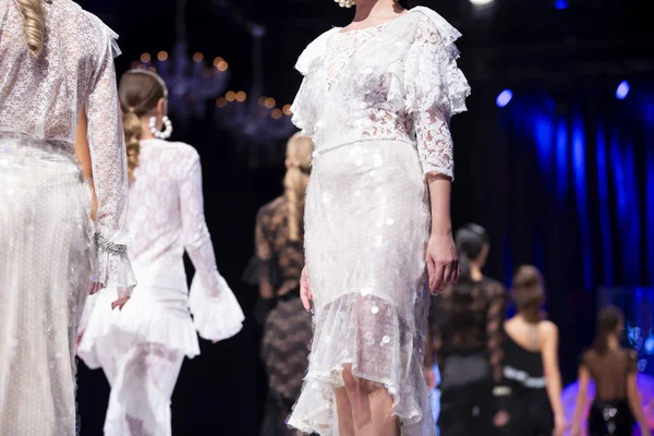 女性モデルは ファッションのショーの間に別の白ドレスで滑走路を歩きます 新しい服のコレクションを示すファッション キャットウォーク イベント — ストック写真