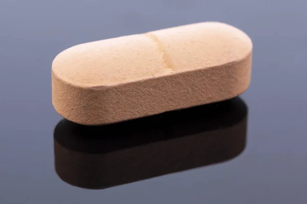 Enkele Beige Pil Geïsoleerd Zwart Reflecterend Oppervlak Wereldwijde Farmaceutische Industrie — Stockfoto