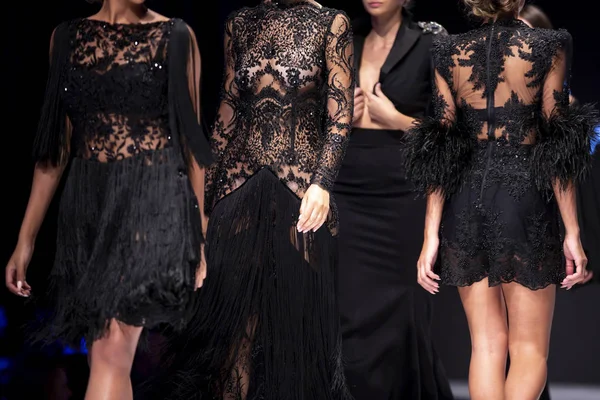 女性モデルは ファッションのショーの間に別の黒ドレスで滑走路を歩きます 新しい服のコレクションを示すファッション キャットウォーク イベント — ストック写真