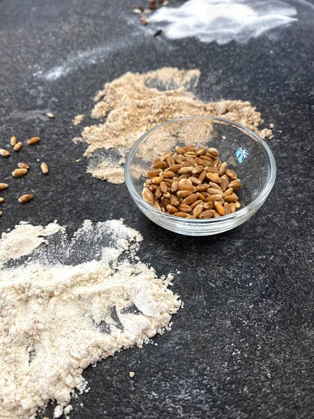 Grains and flour, various types of grains and flours on a black textured stone. Wheat, wheat and rye flour.