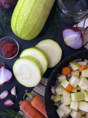 Kabak havyarı pişiriyorum. Sebze iliği tabağı hazırlamak için gerekli malzemeler. Kırmızı soğan, havuç, sarımsak karanfil ve kabak. Siyah desenli taş bir yüzey..