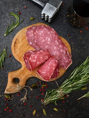 Biberiye ve biberiyeyle ahşap bir tahtada ince dilimlere kesilmiş taze çiğ füme salçalı sosis..