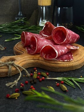 Biberiye ve biberiyeyle ahşap bir tahtada ince dilimlere kesilmiş taze çiğ füme salçalı sosis..