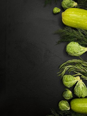Siyah taşlı yüzeyde taze yeşil sebzeler. Düzgün beslenme ve vejetaryenlik kavramı. Brüksel lahanası ve taze yeşillikler..