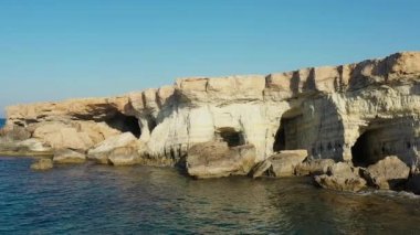 Akdeniz adasının taşlı sahillerindeki deniz mağaraları, ağır çekim, insansız hava aracının görüntüsü