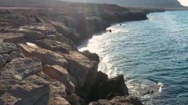 Akdeniz adasının taşlı sahillerindeki deniz mağaraları, ağır çekim, insansız hava aracının görüntüsü