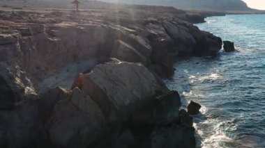 Akdeniz adasının taşlı sahillerindeki deniz mağaraları, ağır çekim, insansız hava aracının görüntüsü