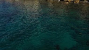 Akdeniz adasının taşlı sahillerindeki deniz mağaraları, ağır çekim, insansız hava aracının görüntüsü