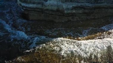Akdeniz adasının taşlı sahillerindeki deniz mağaraları, ağır çekim, insansız hava aracının görüntüsü