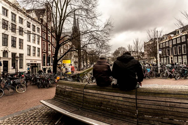 Amsterdam Holandia Lutego 2010 Ludzie Siedzący Szczycie Ławki Patrzący Kanał — Zdjęcie stockowe