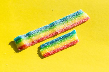 Sarı arka plandaki şekerde renkli marmelat. Doğal gökkuşağı renkli marmelat şekeri. Boşluğu kopyala, metin için boş şablon