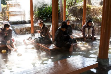 Beppu, Japonya - 29 Aralık 2009: Japonya 'nın Beppu bölgesindeki Kannawa bölgesinde sıcak kaynak Jigoku volkanik su havuzu yakınında oturan insanlar.