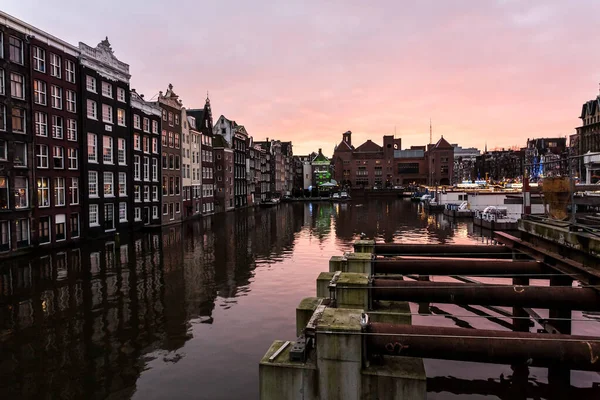 Ámsterdam, Países Bajos - 11 de diciembre de 2009: Puesta de sol rosa en Ámsterdam, calle cerca del canal de agua, las casas se reflejan en el agua. — Foto de Stock