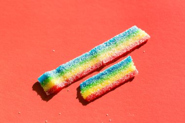 Kırmızı arka plandaki şekerde renkli marmelat. Doğal gökkuşağı renkli marmelat şekeri. Boşluğu kopyala, metin için boş şablon