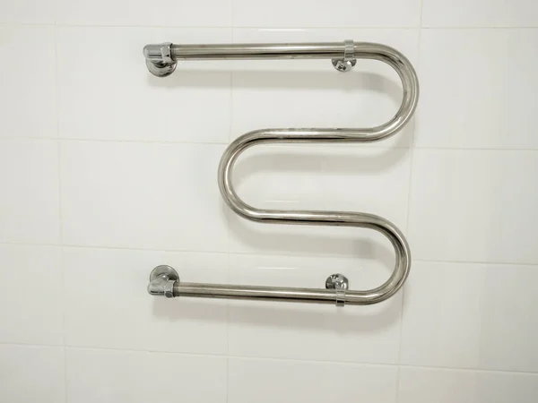 New heated towel rail on the white tiled wall, renovation concept