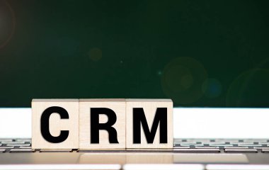 CRM Müşteri İlişkileri Pazarlama bir dizüstü bilgisayarın önündeki tahta küpte yazılı.