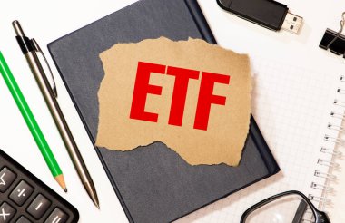 İş ve finans kavramı. Hisse senedi piyasasında ticaret yapabilen ETF Ticaret Fonu eş zamanlı endeks fonu ile yazılan hesap makinesi, cep telefonu, kalem ve not defterinin üst görünümü.