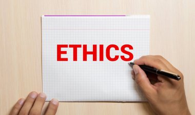 Kırmızı kalemle. Kahve fincanı. Kal. Klavye ve beyaz arka plan. Not defterinde ETHICS işareti.
