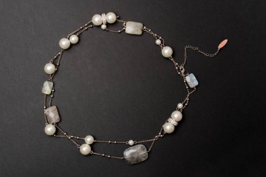 Siyah bir zemin üzerine taş ve inci kolye