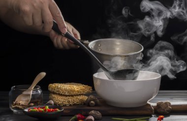 Şef, ahşap bir masa üzerinde acı biberli ve limonlu Shiitake soslu sıcak çorba eriştesi hazırlıyor..