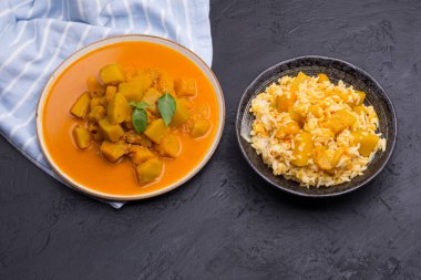 Siyah zemin üzerinde seramik tabakta servis edilen pirinçli köri ya da balkabağı çorbası..