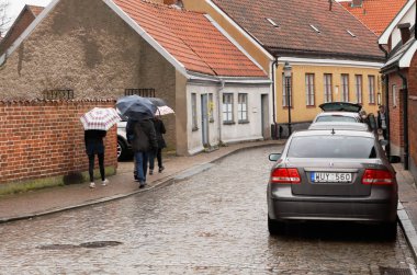 Ystad, İsveç - 15 Nisan 2017: Bir grup insan onların şemsiye şehir Ystad yağmurla yürüyüş.