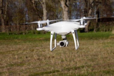Tullgarn, İsveç - 6 Mayıs 2018: Bir beyaz ile DJI indeks işlem Phantom 4 quadcopter ileri zemin seviyesine uçan işaret onun fotoğraf makinesi ile.