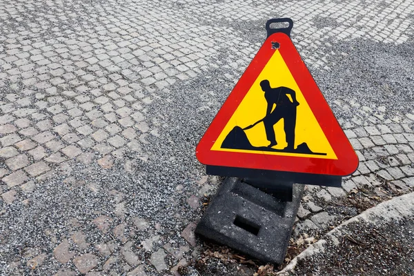 砂利の上で Cobbelstones と舗装された通りに置かれた一時的な道路工事警告サインの形を三角形の高いエンジェル ビュー — ストック写真