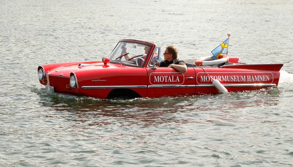 Motala, İsveç - Auguist 8, 2015: İki kişi suda sürüş ile bir kırmızı Amphicar.