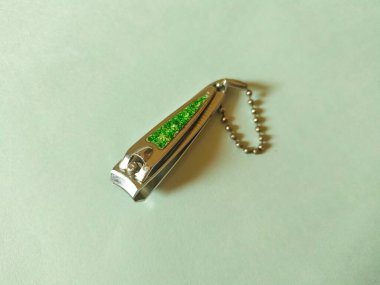 Çelik tırnak makası arkaplanda izole edilmiş. Üstte yeşil tasarım ve asmak için top zinciri.