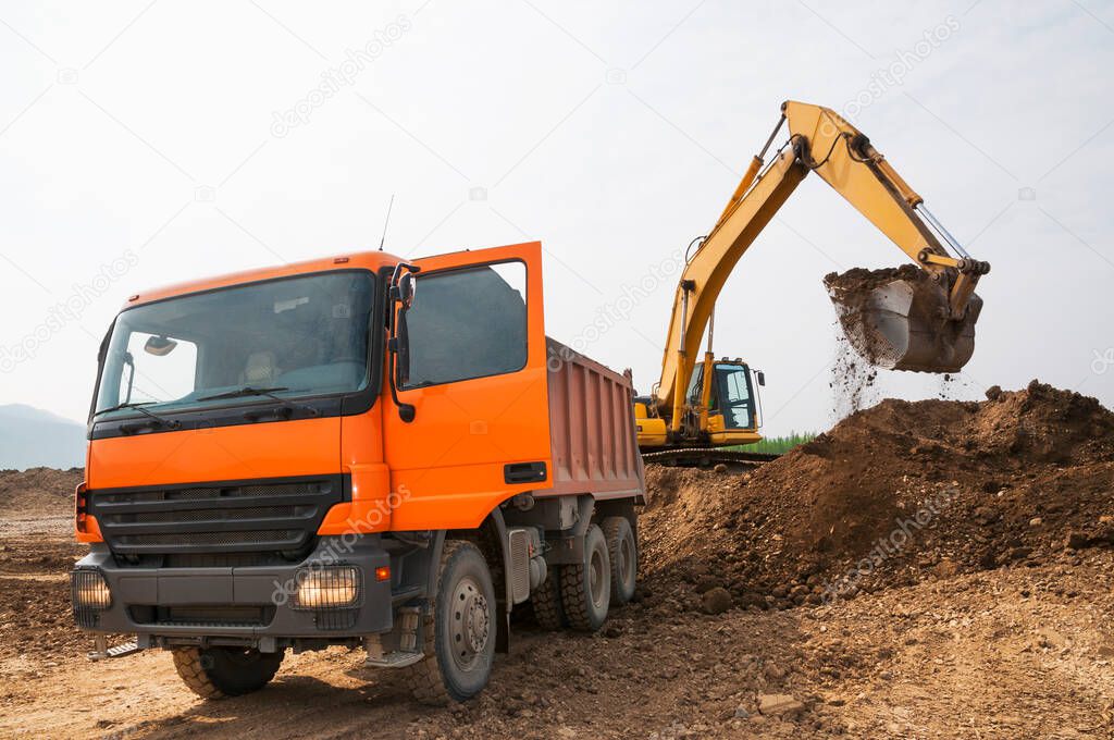  Loading of earth soil into the body of a cargo dump truck by an excavator bucket