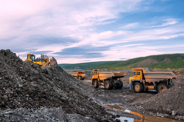 Tekerlek yükleyicisi dağ toprağını arkaya yüklüyor, madenci kamyonları daha fazla işlemek için dağ toprağı taşıyor
