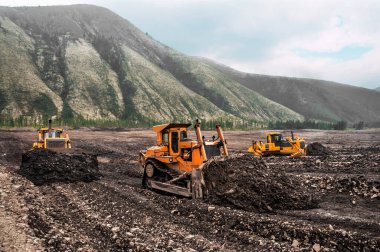  Dağlık ormanlık alanlarda buldozerler, katman katman, dağ toprağını yüzeyden çıkarıp kenara doğru kürekliyorlar..