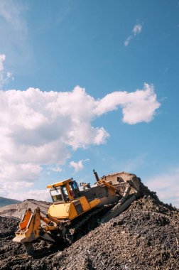  Dağlık bölgelerdeki buldozerler, katman katman, dağ toprağını yüzeyden çıkarıp kenara doğru kürekliyorlar..