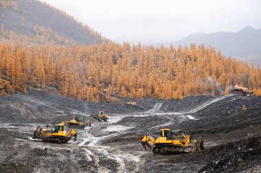 Dağlık ormanlık alanlarda buldozerler, katman katman, dağ toprağını yüzeyden çıkarıp kenara doğru kürekliyorlar..