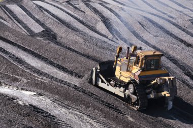 Dağlık alanda buldozer, katman katman, dağ toprağını yüzeyden çıkarıp kenara doğru kürekleyin..