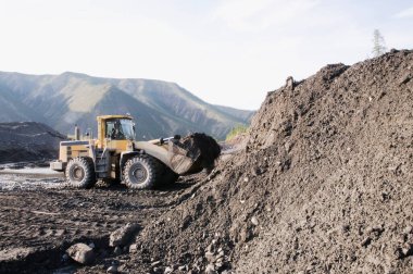 Dağlık bir orman bölgesinde doğal altın madenciliği. Buldozerler, güneşli bir yaz gününde bir dağ ormanında çalışma sürecinde.