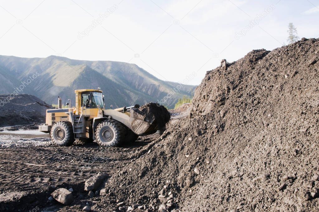 Mining of natural gold in a mountainous forest area. Bulldozers in the process of working in a mountain forest area on a summer sunny day