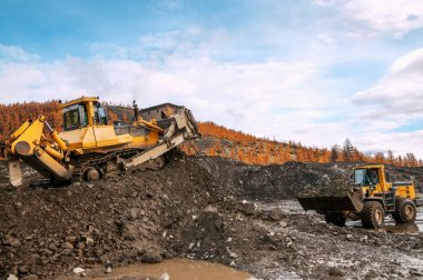 Dağlık alanlarda doğal altın madenciliği yapan Buldozer, doğal altın yoğunluğunun arttığı dağ toprağını toplar. Sonra, tekerlek yükleyiciler bu dağ toprağını yıkamak için özel endüstriyel ekipmanlara taşıyorlar.