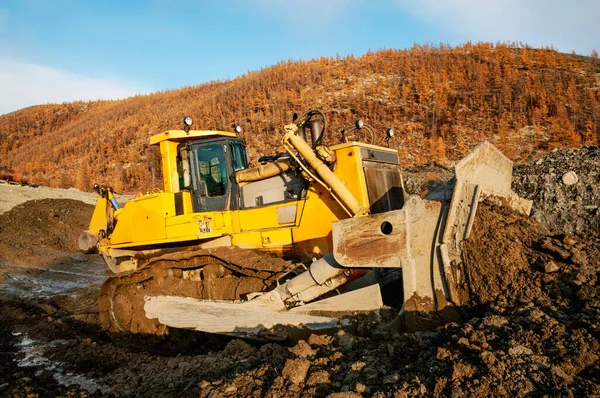 Open pit mining natural gold in mountainous areas Bulldozer collects heap of mountain soil in which there is increased concentration of natural gold (Aurum). Then, wheel loaders transport this mountain soil to special industrial equipment for washing