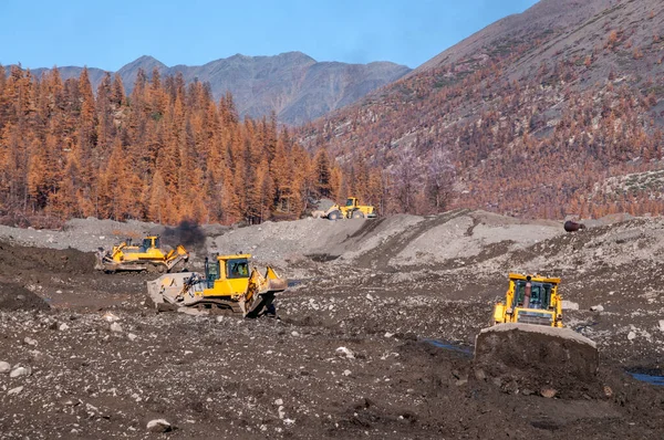 Dağlık alanlarda doğal altın madenciliği yapan Buldozer, doğal altın yoğunluğunun arttığı dağ toprağını toplar. Sonra, tekerlek yükleyiciler bu dağ toprağını yıkamak için özel endüstriyel ekipmanlara taşıyorlar.